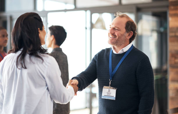 shot of a mature businessman shaking hands with an attendee at a conference - tradeshow imagens e fotografias de stock