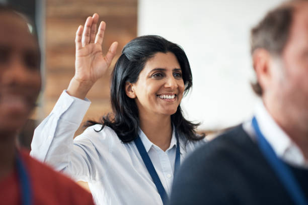 aufnahme einer reifen geschäftsfrau, die während einer konferenz die hand hebt - seminar presentation asking business stock-fotos und bilder