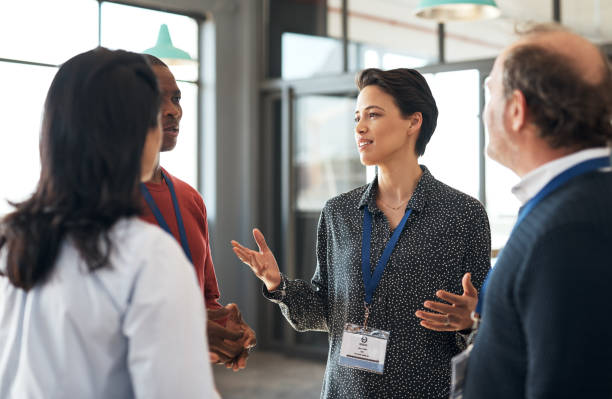 Shot of a group of businesspeople networking at a conference Taking the opportunity to share more about her brand conference event stock pictures, royalty-free photos & images