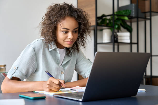 istock Young African girl student learning class on laptop watching webinar at home. 1335876736