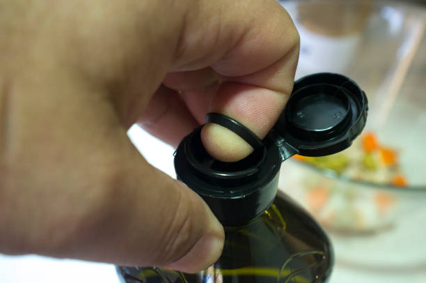 istock Finger opening a sealed olive oil bottle with an inner pull-off plastic tab underneath the cap 1335877090