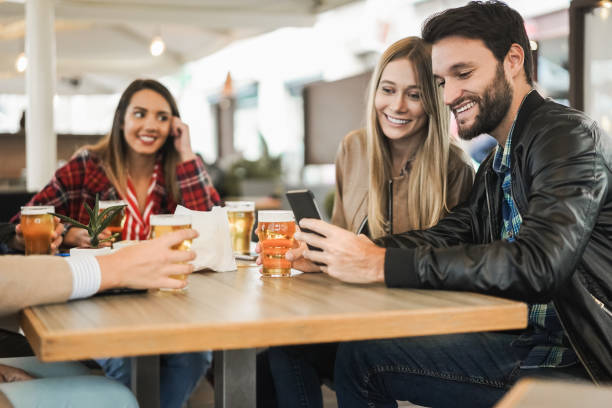 istock Young people having fun using mobile phone while drinking beer at bar restaurant - Focus on man face 1335879343