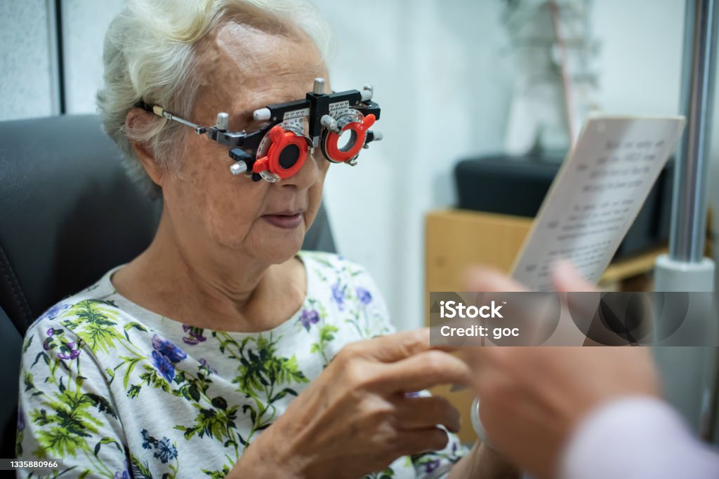 Senior Chinese woman checking eyes vision in ophthalmological clinic Optometrist using phoropter to check eyesight value for a senior Chinese woman before making new eyeglasses in optical shop Senior Adult Stock Photo
