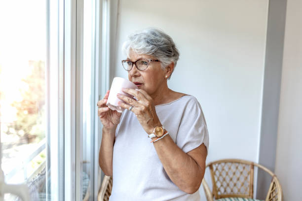 istock Depressed lonely lady standing alone and looking through the window. 1335881209