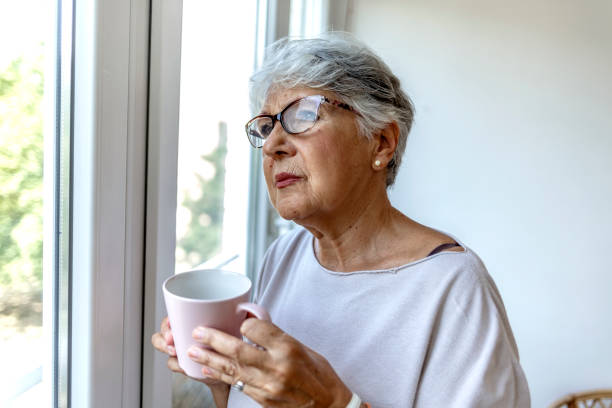 istock Depressed lonely lady standing alone and looking through the window. 1335881217