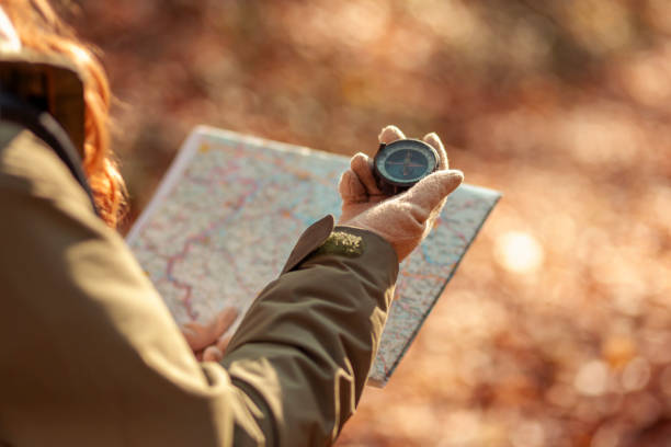 istock Woman holding a compass and reading a map while hiking 1335881498