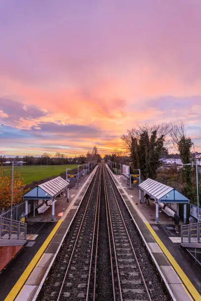 A coloured beautiful view of a sunset over a railway at the tube station, the shot is taken from a below level, the sky is colourful.