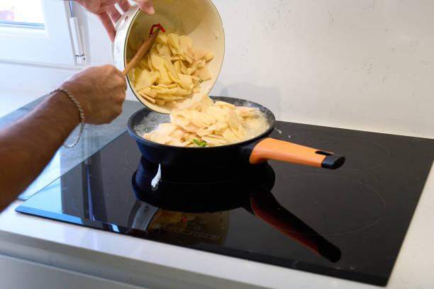 istock Hands of a man adding potatoes sliced into a frying pan 1335891831