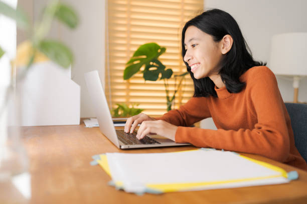 chica asiática usando computadora portátil en casa por la mañana - child computer internet laptop fotografías e imágenes de stock