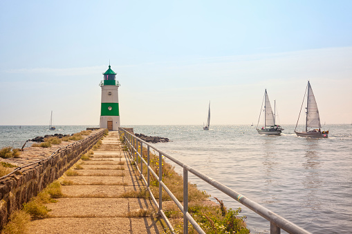 Lighthouse of Schleimünde between baltic Sea and Schlei inlet on a bright sunny day, sail boats passing by