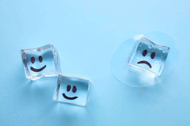 istock Ice cubes with drawn faces on light blue background, flat lay. Concept of jealousy 1335894553