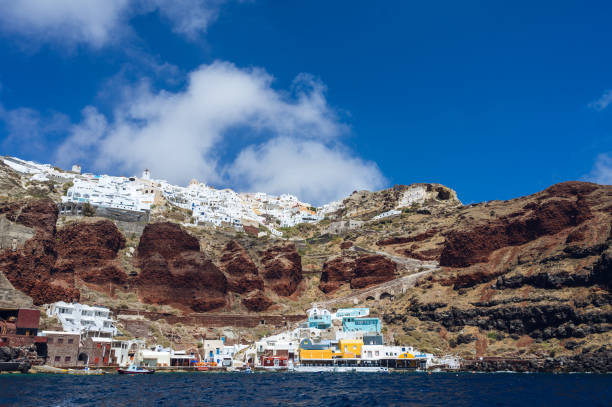 blick vom meer auf den hafen von oia. santorini, griechenland. einzigartige architektur. boote im wasser. treppe auf dem felsen. - caldera stock-fotos und bilder