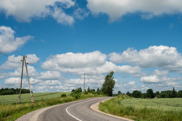 istock Countryside landscape. Empty asphalt road. Summer nature. Blue cloudy sky. Green trees. Haystack on grass. 1335896865