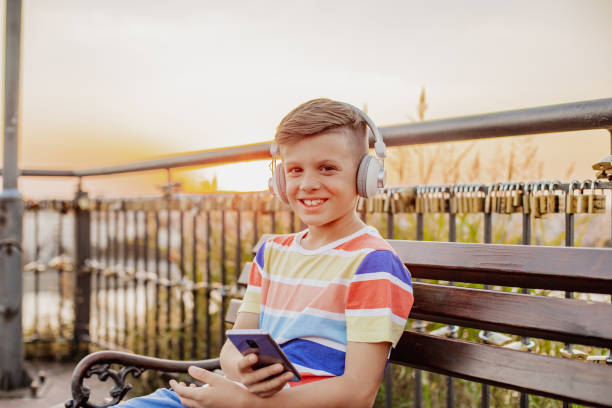 istock Little boy is using mobile phone on the bench 1335897211
