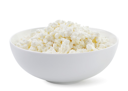 Cottage cheese in a plate close-up on a white background. Isolated