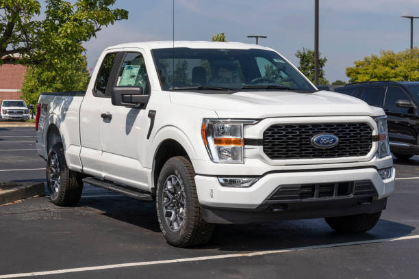 ford f-150 display at a dealership. the ford f150 is available in xl, xlt, lariat, king ranch, platinum, and limited models. - domestic car color image horizontal car imagens e fotografias de stock