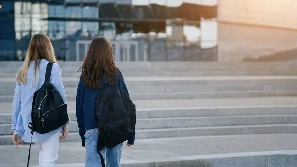 Two teenage student friends girls happy going to college or school