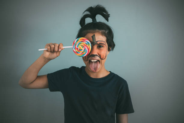 istock Girl in pumpkin makeup with a lollipop 1335900106
