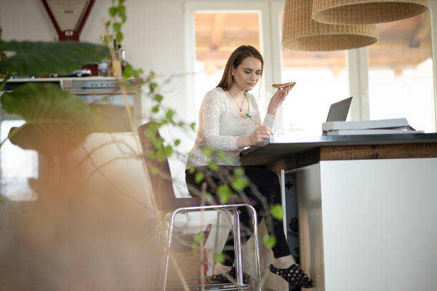 istock Woman eating take-out pizza and working from home 1335900212