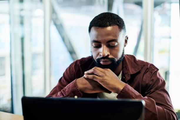 istock Shot of a young businessman lost in thought while using a laptop in a modern office 1335901648