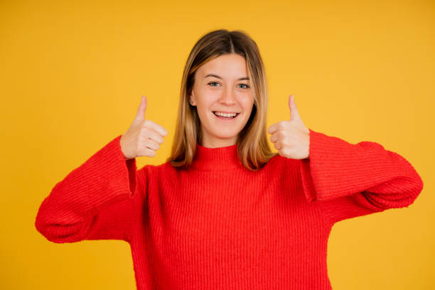 istock Young woman smiling while showing thumbs up to camera. 1335905137