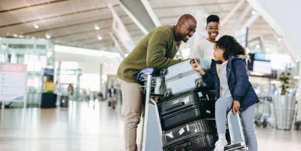 Tourist family with luggage trolley at airport Father and mother waiting with young daughter at airport. Tourist family at airport terminal with luggage holiday. travel destinations stock pictures, royalty-free photos & images