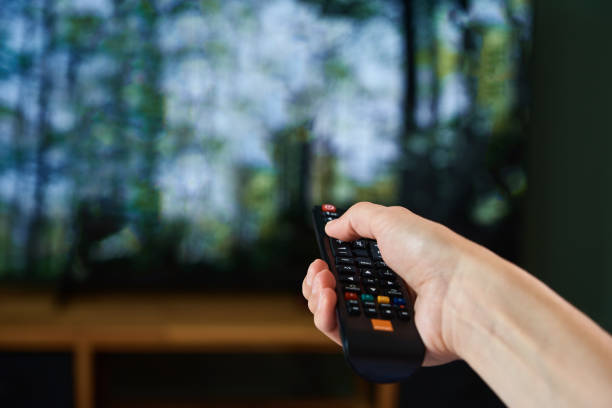 istock Woman switch TV set with remote control 1335920877