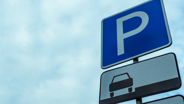 istock Blue road sign with letter P on rectangular plate isolated against a blue sky. Parking symbol on a cloudy blue sky background. Space for text. 1335921223