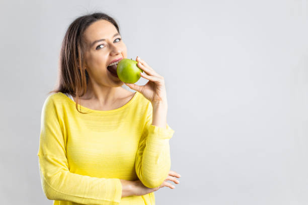 молодая женщина ест зеленое яблоко - apple women green eating стоковые фото и изображения