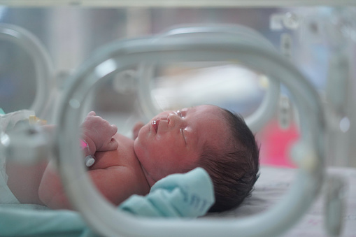 Bebé recién nacido, su cuerpo está rojo durmiendo en la cuna del hospital, en la sala de partos en el hospital. photo