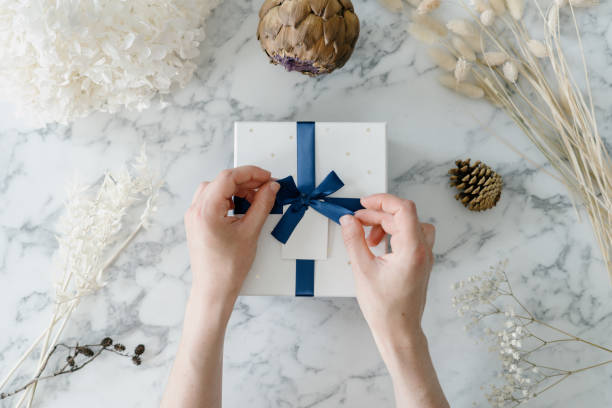 woman tying blue bow on white gift box - hand wrap imagens e fotografias de stock