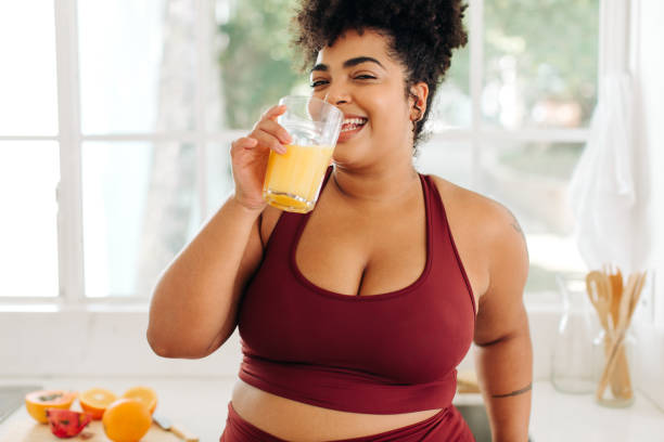 Attractive fitness woman having fruit juice at home