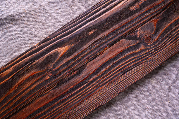 A dark brown brushed board lies on a gray burlap, top view