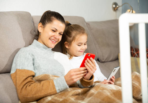 istock Mom and small daughter using smartphone in home 1335932524
