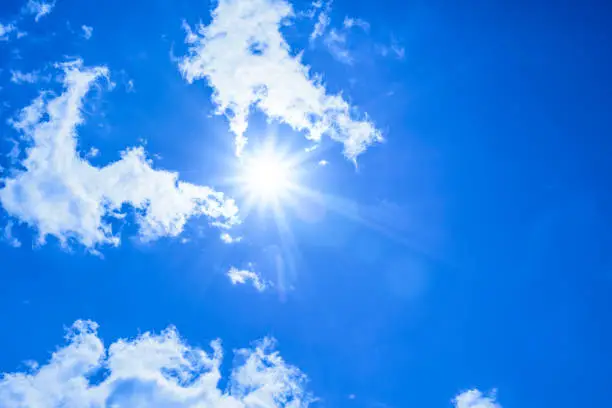 Photo of Bright sun with beautiful beams in the sky with light clouds