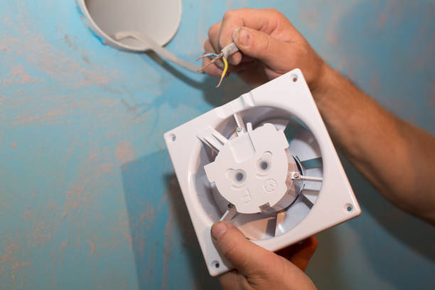 istock Man is installing the wall bathroom fan vent. Restoration process. Wires in hands. Maintenance repair works renovation in the flat. 1335935144