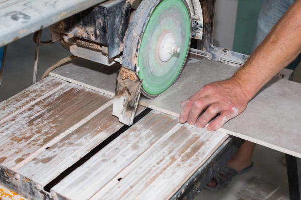istock A worker is cutting a ceramic tile on a special electric wet water cutter saw machine. Maintenance repair in the flat. Renovation process. 1335935236