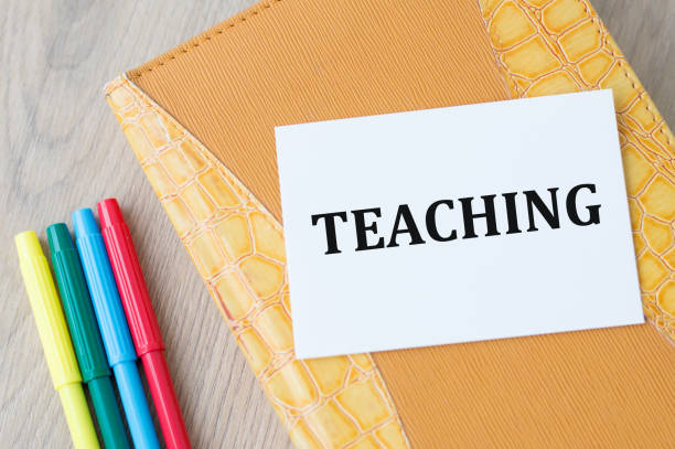 istock On the card text Teaching, which lies on a closed notebook on the table next to colored markers 1335938565