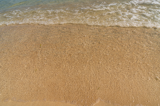 Soft waves with foam of blue sea on the sandy beach