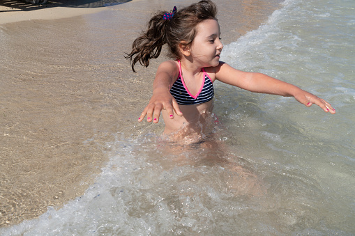 Happy toddler girl having fun in the sea