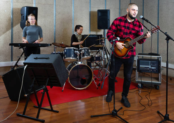 istock Guy guitar player and singer practicing with band members in recording studio 1335941009