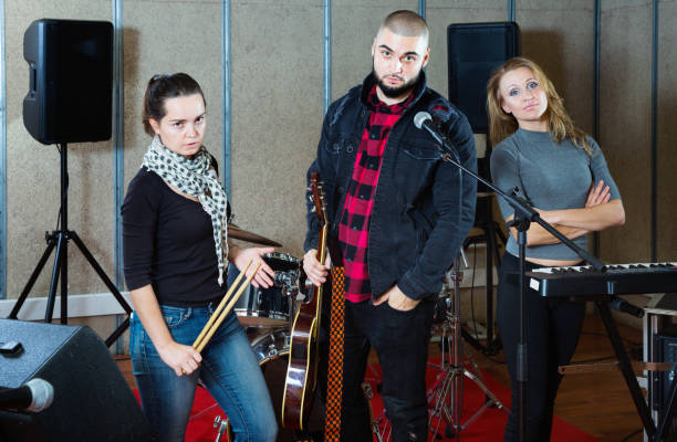 istock Three bandmates posing together with musical instruments in rehearsal room 1335941025
