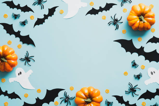 istock Happy Halloween holiday concept. Flat lay composition with pumpkins, bats, ghosts, spiders on blue background. Top view with copy space. 1335941062