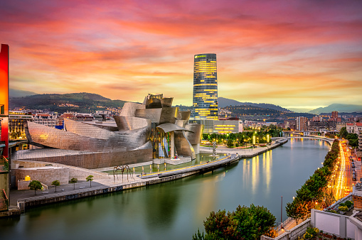 The cityscape of Bilbao at sunset, Spain. The Nervion river crosses Bilbao downtown, hosting in its margins the traditional and modern buildings of the city with  Guggenheim museum and Iberdrola tower