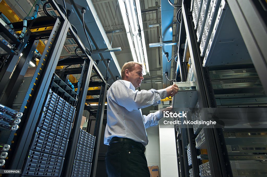 Server expansion IT administrator installing a new rack mount server. Large scale storage server is also seen. IT Support Stock Photo