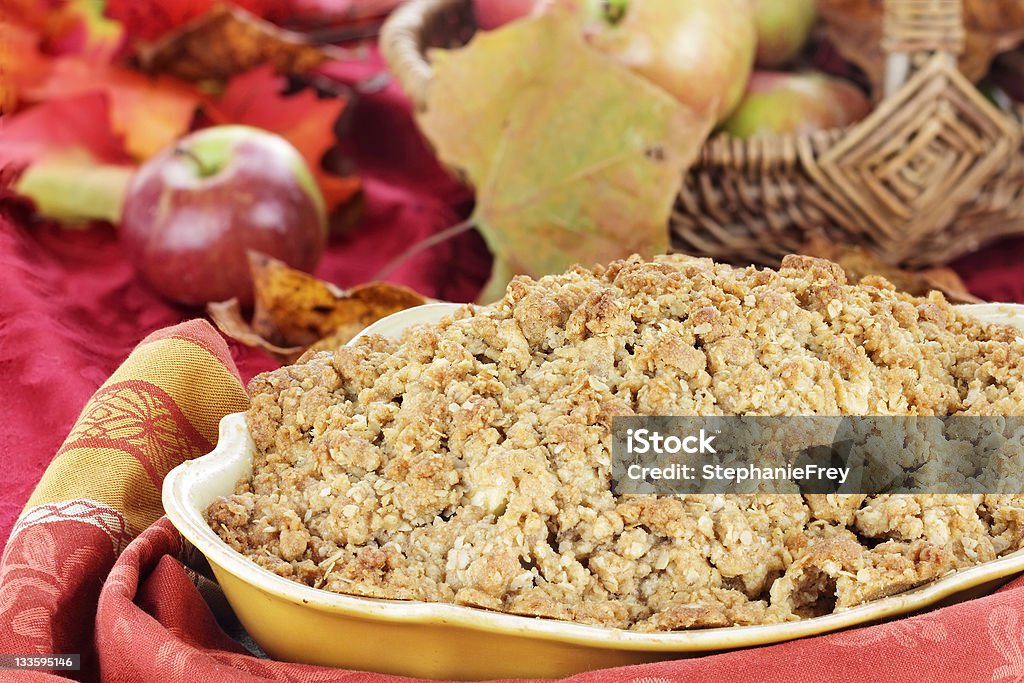 Apple Crisp Freshly baked apple crisp with fresh apples and autumn leaves in the background. Shallow depth of field with selective focus on the foreground. Apple Crumble Stock Photo