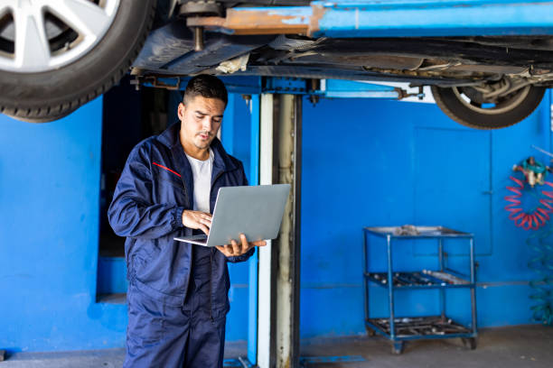 portret młodego mechanika korzystającego z laptopa w swoim warszcie samochodowym - vehicle suspension zdjęcia i obrazy z banku zdjęć
