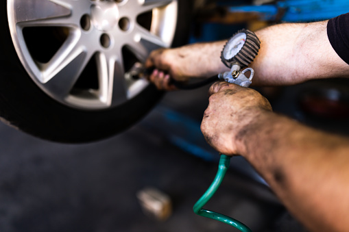 Close up of mechanic's hand checking the air pressure of a tyre in auto repair service