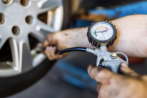 Primer plano de la mano del mecánico comprobando la presión de aire de un neumático en el servicio de reparación de automóviles photo