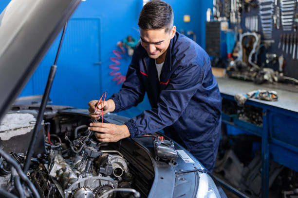 o mecânico do carro está usando um multimetro com medição de faixa de tensão para verificar o nível de tensão da bateria do carro. - repairing auto repair shop service technician - fotografias e filmes do acervo